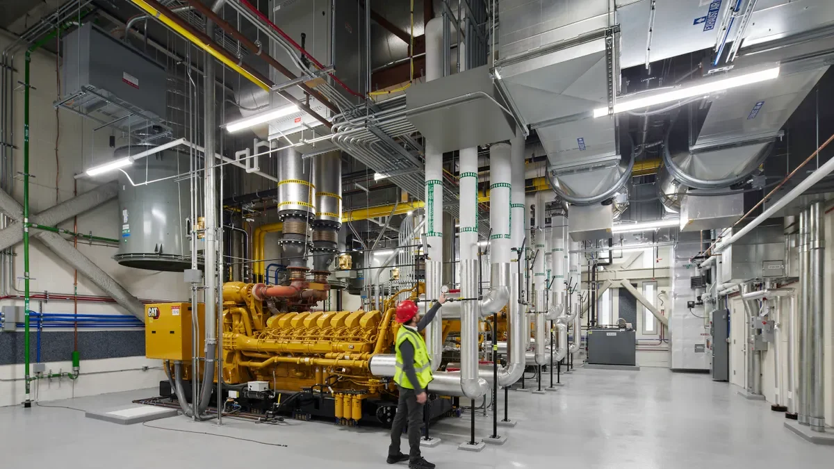 An interior of an industrial setting with pipes and steel-colored machinery.