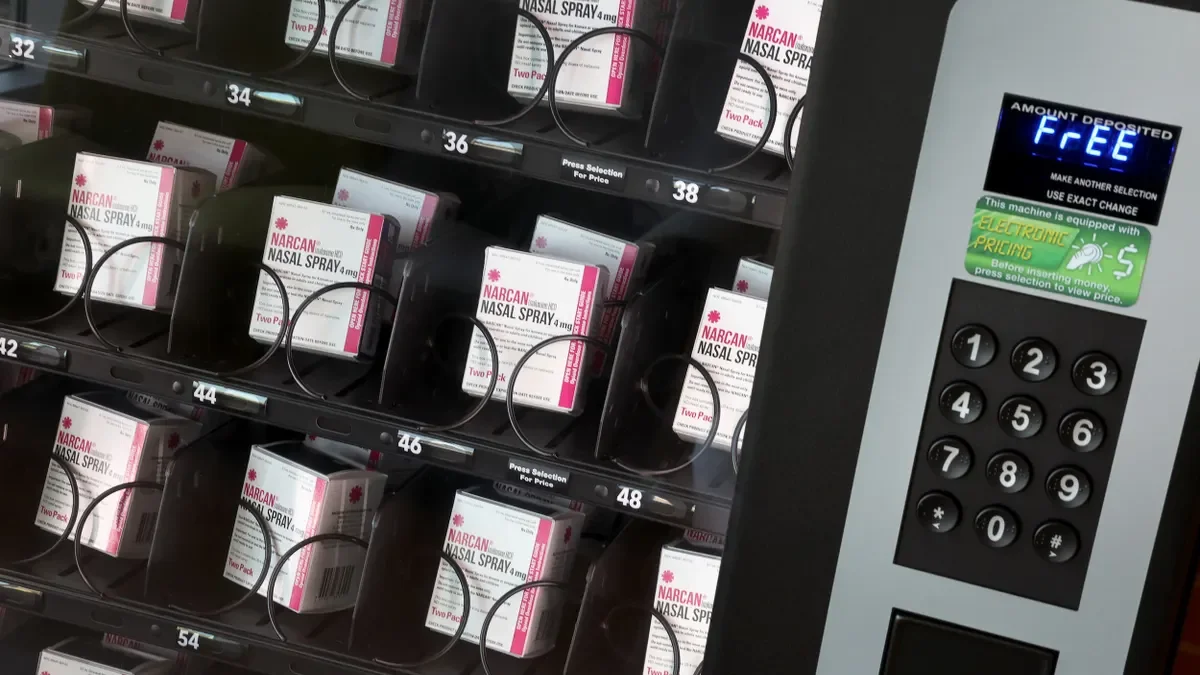 Boxes labeled "Narcan nasal spray" in a vending machine with the word "Free" displayed in digital letters.
